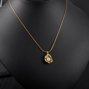 Elegant gold collar necklace with organic shape pendant and pearl on black neck display