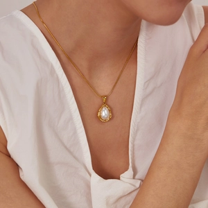 Collier vintage français avec pendentif perle en acier inoxydable doré sur un mannequin
