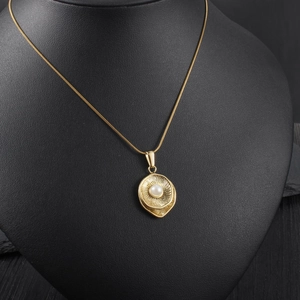 Elegant gold pearl necklace with textured leaf pendant on black mannequin display