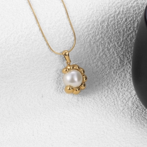 Élégant collier à pendentif en forme de C doré avec perle blanche sur fond de pierre
