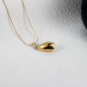 Collier pendentif goutte d'or poli avec chaîne serpent sur un fond de texture en pierre