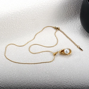 Détail du collier chaîne serpent dorée avec pendentif goutte irrégulier et perle blanche