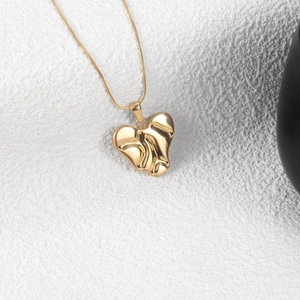Lava texture heart pendant necklace in gold finish on a minimalist white background