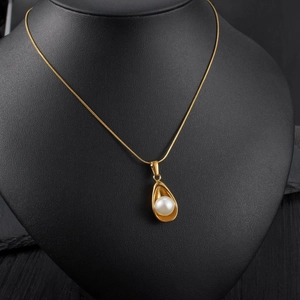 Collier élégant en or avec pendentif perle irrégulière sur un présentoir de buste noir