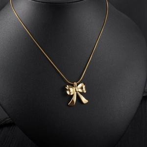 Elegant polished gold bow necklace displayed on a black neck bust for a premium look