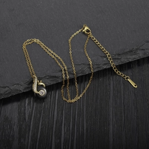 Detailed view of musical note pendant with gold chain and crystals on a dark stone surface