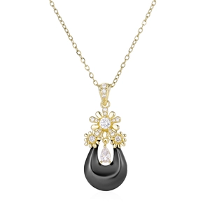 Détail du pendentif goutte en céramique avec fleur dorée et pierre de zircon brillante