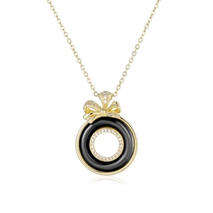 Macro detail of gold bow necklace with black enamel inlay and micro-pave crystals