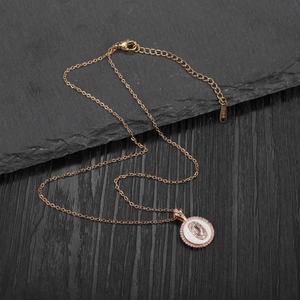 Detail of rose gold layered round pendant with crystals and S-STEEL engraved tag