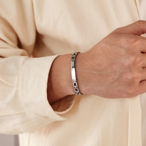 Gros plan d'un bracelet d'identité en acier inoxydable porté sur une chemise en lin