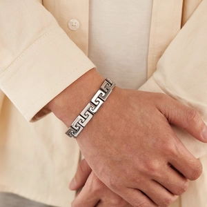 Close-up of men's stainless steel bracelet featuring Greek meander hollow patterns