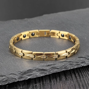 Bracelet magnétique doré avec strass en forme de goutte d'eau sur fond de pierre grise