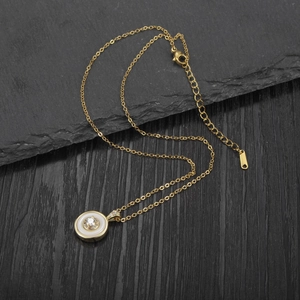 Detail of gold circle necklace with white shell inlay and crystals on dark stone surface