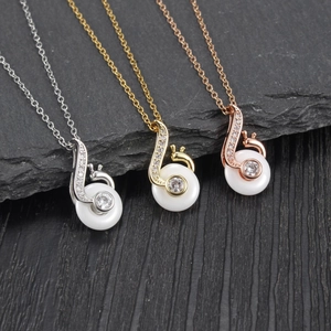 Three elegant snail musical note pendants in silver, gold, and rose gold with tiny crystals