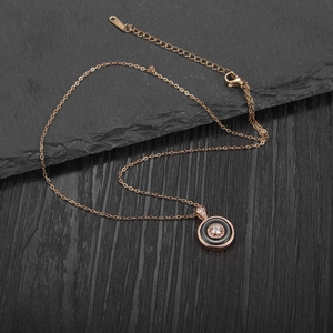 Detail of rose gold necklace featuring a circular pendant with black inlay and crystal