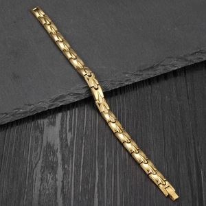 Détail du bracelet goutte plaqué or avec zircons cubiques sur un fond de pierre sombre