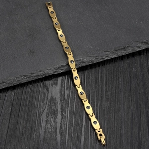 Makroaufnahme von vergoldetem Titanstahl-Armband mit schwarzen Magnetsteinen und Klappverschluss