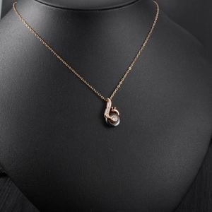 Macro detail of rose gold swan pendant with black inlay and sparkling white cubic zirconia