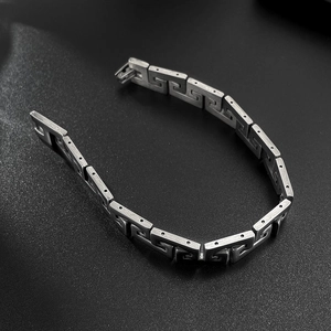 Macro detail of men's stainless steel bracelet with Greek key pattern and brushed finish