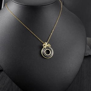 Macro detail of golden bow necklace with black ceramic circle and white cubic zirconia