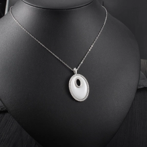 Gros plan du pendentif ovale évidé serti de micro diamants sur une chaîne argentée