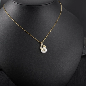 Detail of a gold snail necklace pendant with white enamel inlay and sparkling crystals