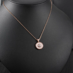 Detail view of a rose gold necklace featuring a round pendant with mother-of-pearl and diamonds