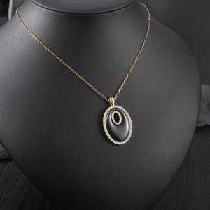 Détail du collier pendentif ovale doré élégant avec agate noire et cristaux brillants
