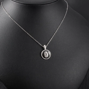 Detail shot of a layered circular pendant with rhinestones and black inlay on a neck model
