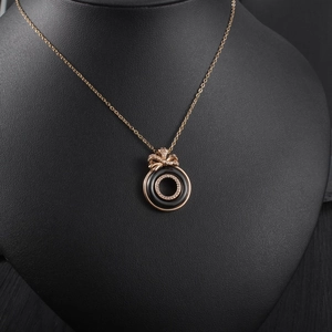 Detail of rose gold necklace with black enamel ring and crystal butterfly pendant