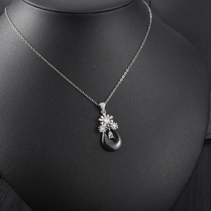 Gros plan du pendentif en céramique goutte d'eau avec motif floral argenté sur modèle