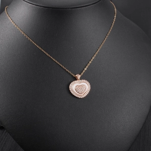 Detail of rose gold heart pendant with crystal pavé and white inlay on velvet stand