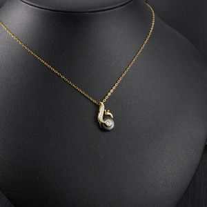 Macro detail of melody note necklace with black pearl and sparkling swan crystal inlay