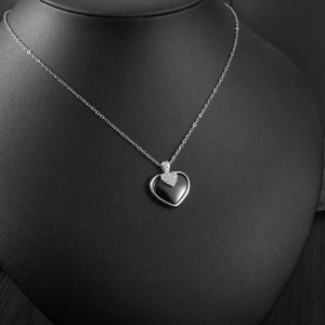 Gros plan du pendentif double cœur en céramique avec onyx noir sur chaîne argent
