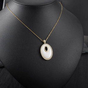 Détail d'un collier avec pendentif ovale doré serti de diamants et émail blanc chic