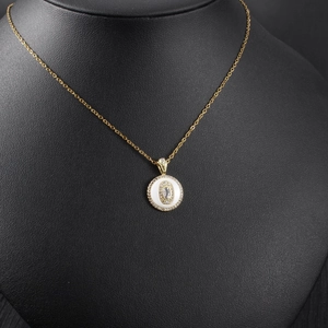Close-up of golden circular pendant with white enamel and center oval cubic zirconia