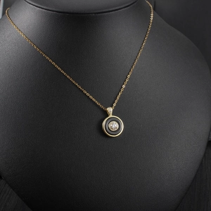 Detail of a gold circular necklace with black ring and sparkling crystal pendant inlay
