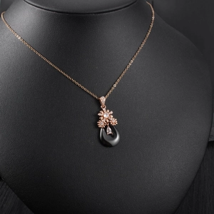 Détail du pendentif fleur en or rose avec pierre noire en forme de goutte et cristal incrusté