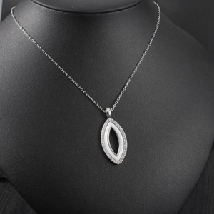 Détail macro du pendentif marquise argenté avec céramique blanche et cristaux pavés brillants