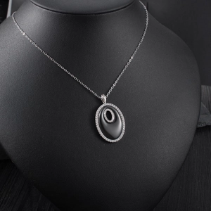 Détail d'un collier chaîne argentée avec pendentif ovale noir orné de zircons brillants