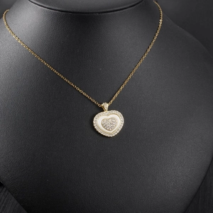 Close-up of heart pendant necklace with shimmering crystals on a black jewelry display stand