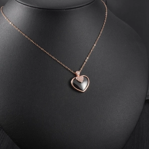 Détail du collier double cœur en or rose avec pendentif noir sur support professionnel