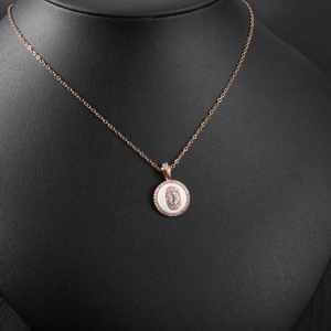 Detail of rose gold round pendant with crystal inlay on black jewelry display stand