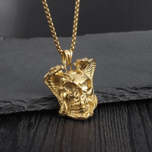 Detailed close-up of golden cobra and skull pendant on dark slate background