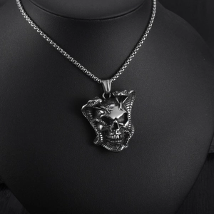 Macro shot of gothic skull and coiled python pendant on a black velvet necklace display stand