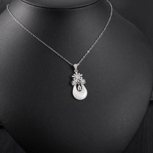 Détail du collier argenté avec charmes floraux en zircon et pendentif diamant en goutte