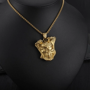 Detailed close-up of gold gothic skull pendant with entwined cobras on a black model