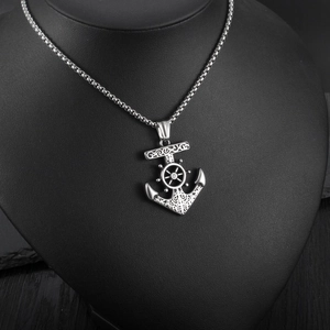 Dettaglio del ciondolo a forma di ancora in argento con timone e catena su supporto nero