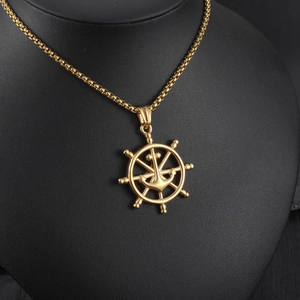 Close-up of golden ship rudder and anchor pendant on black necklace mannequin stand