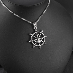 Detailed shot of punk style stainless steel ship wheel and anchor pendant on a black bust